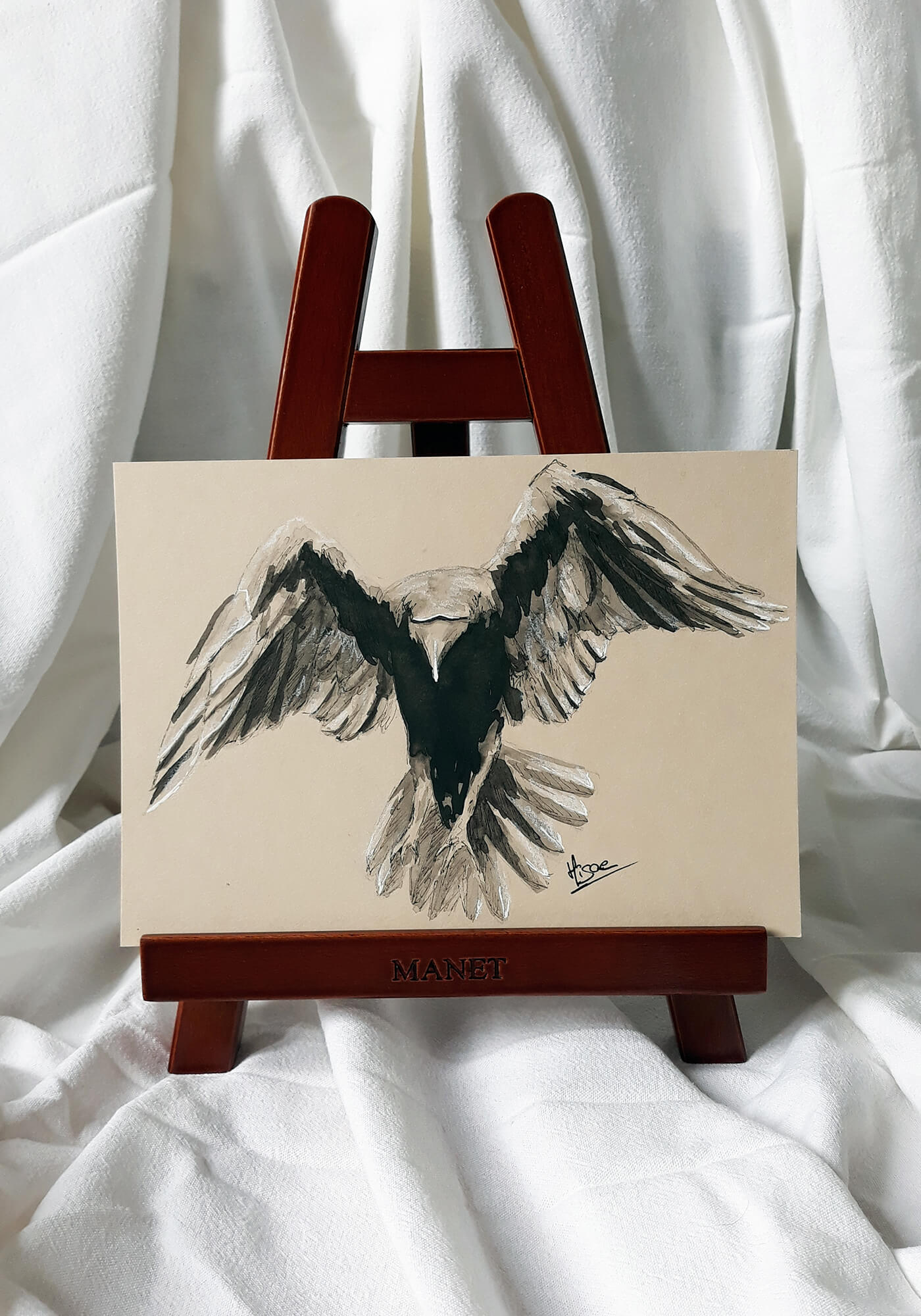 Dessin original à l'encre de Chine et crayon blanc sur chevalet représentant un corbeau de dos en train de s'envoler ©Hisae illustrations